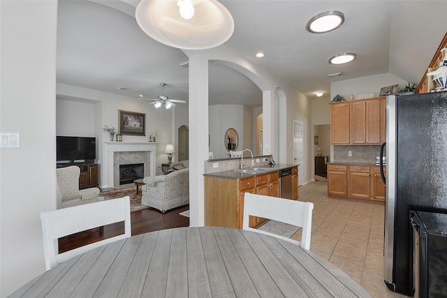 8810 Sailing Dr, Humble, TX 77346 - kitchen with stainless steel appliances, a sink, arched walkways, a fireplace, and ceiling fan