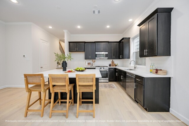 1818 Colquitt St, Houston, TX 77098 - kitchen featuring stainless steel appliances, a sink, light wood-style floors, crown molding, and a center island