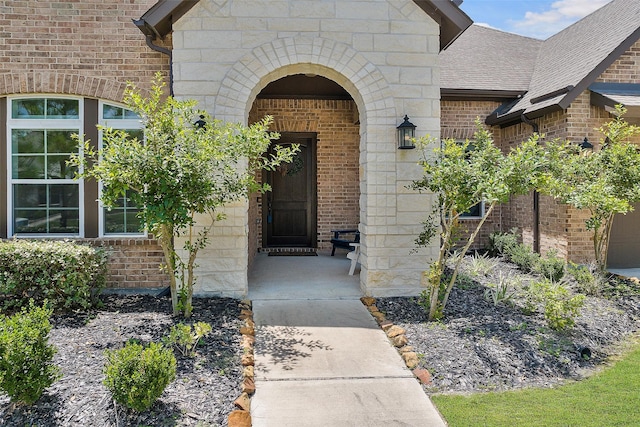 15240 Hemingway Heights Dr, Conroe, TX 77302 - view of exterior entry featuring brick siding, stone siding, and roof with shingles