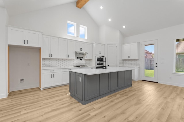 15240 Hemingway Heights Dr, Conroe, TX 77302 - kitchen with stainless steel appliances, white cabinets, light countertops, high vaulted ceiling, and decorative backsplash