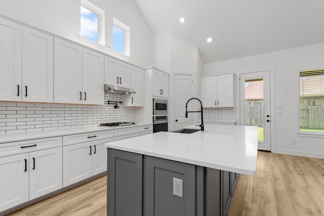 15240 Hemingway Heights Dr, Conroe, TX 77302 - kitchen with stainless steel appliances, a sink, light countertops, light wood-style floors, and white cabinetry