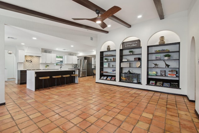 6222 Queensloch Dr, Houston, TX 77096 - unfurnished living room featuring beamed ceiling, ceiling fan, recessed lighting, built in shelves, and light tile patterned floors