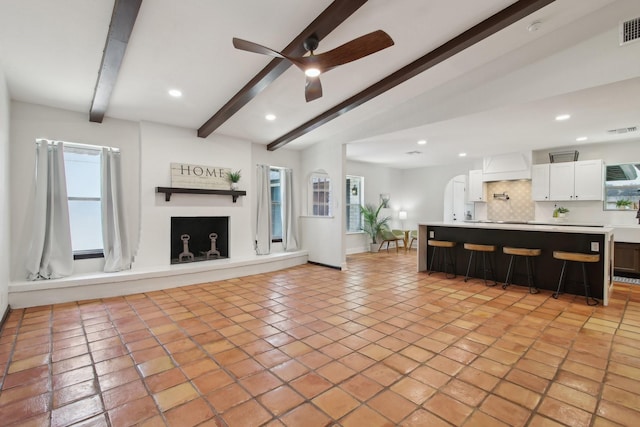 6222 Queensloch Dr, Houston, TX 77096 - unfurnished living room with beam ceiling, a ceiling fan, recessed lighting, a fireplace with raised hearth, and light tile patterned flooring