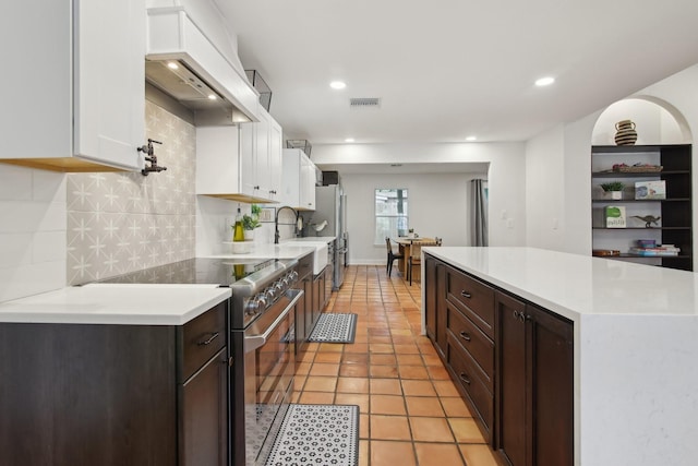 6222 Queensloch Dr, Houston, TX 77096 - kitchen with stainless steel stove, white cabinetry, premium range hood, a sink, and light countertops