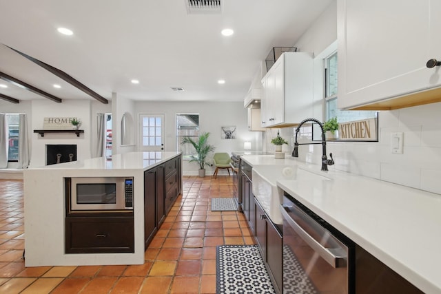 6222 Queensloch Dr, Houston, TX 77096 - kitchen featuring stainless steel appliances, a sink, light countertops, a center island, and white cabinetry
