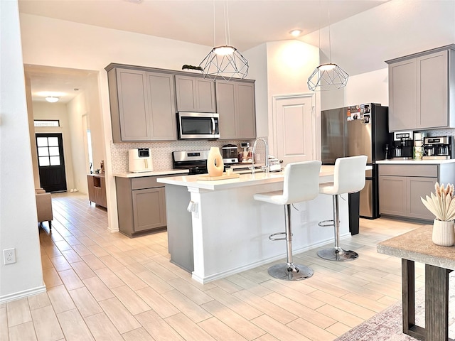 7419 Caprock Canyon Ln, Porter, TX 77365 - kitchen featuring appliances with stainless steel finishes, gray cabinetry, a kitchen breakfast bar, tasteful backsplash, and light countertops