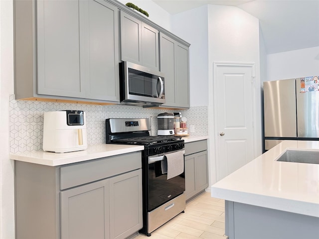 7419 Caprock Canyon Ln, Porter, TX 77365 - kitchen with appliances with stainless steel finishes, gray cabinets, decorative backsplash, and light countertops