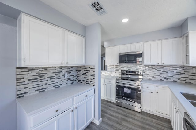 11919 Bald Mountain Cir, Houston, TX 77067 - kitchen featuring stainless steel appliances, white cabinets, light countertops, dark wood-style floors, and recessed lighting