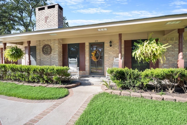 213 Cobb St, Corrigan, TX 75939 - view of exterior entry featuring a chimney, covered porch, and brick siding