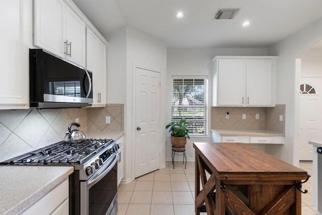6103 Moran Crest Dr, Spring, TX 77388 - kitchen featuring stainless steel gas range, white cabinets, arched walkways, light countertops, and recessed lighting