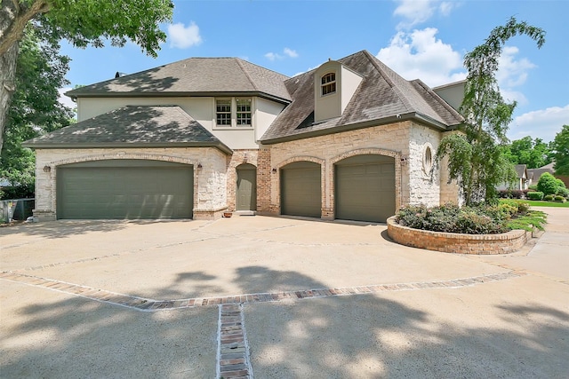 5318 Westerham St, Fulshear, TX 77441 - french country inspired facade with an attached garage, stone siding, concrete driveway, stucco siding, and a shingled roof