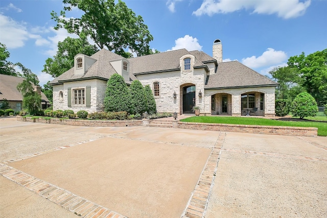 5318 Westerham St, Fulshear, TX 77441 - french provincial home with stone siding, a chimney, and a shingled roof