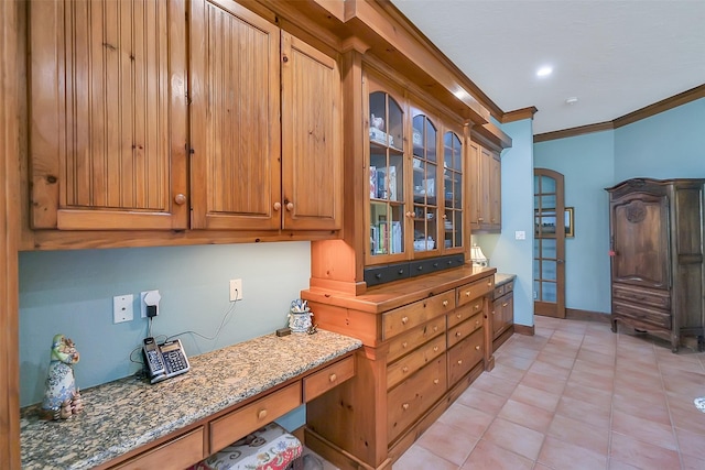 5318 Westerham St, Fulshear, TX 77441 - kitchen featuring ornamental molding, light stone countertops, glass insert cabinets, light tile patterned flooring, and baseboards
