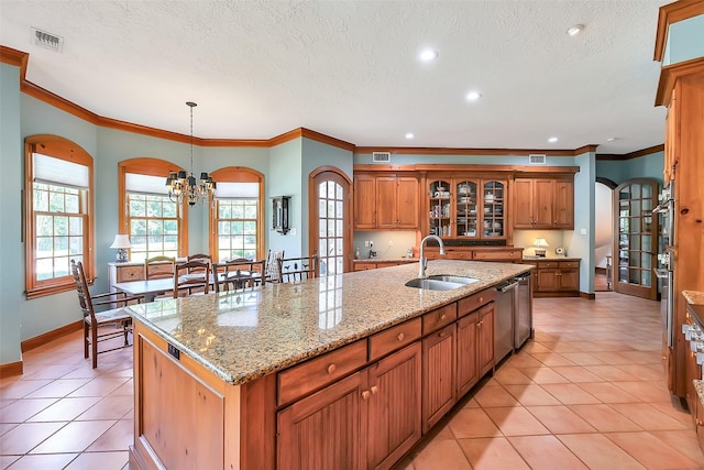 5318 Westerham St, Fulshear, TX 77441 - kitchen with a sink, brown cabinets, a center island with sink, arched walkways, and a chandelier