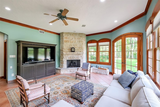 5318 Westerham St, Fulshear, TX 77441 - living area featuring a ceiling fan, light tile patterned flooring, crown molding, a stone fireplace, and french doors
