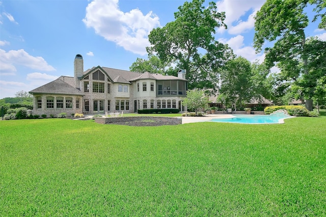 5318 Westerham St, Fulshear, TX 77441 - back of house with a chimney, stone siding, an outdoor pool, and a yard