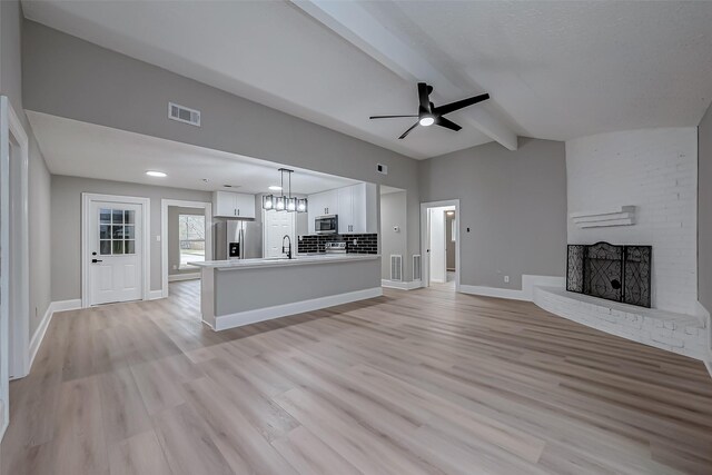 23227 Pine Post Ln, Spring, TX 77373 - unfurnished living room featuring a ceiling fan, light wood-style flooring, a fireplace, a sink, and baseboards