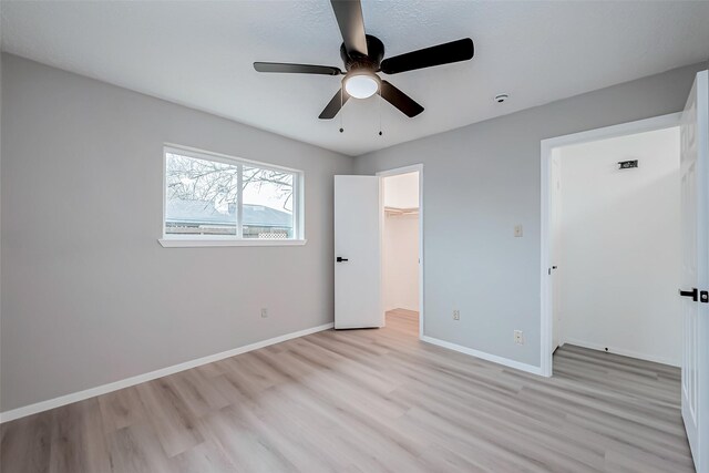 23227 Pine Post Ln, Spring, TX 77373 - unfurnished bedroom featuring light wood finished floors, baseboards, a ceiling fan, a closet, and a spacious closet