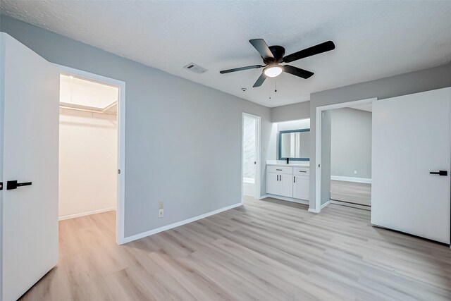 23227 Pine Post Ln, Spring, TX 77373 - unfurnished bedroom with a spacious closet, light wood-type flooring, baseboards, ceiling fan, and connected bathroom