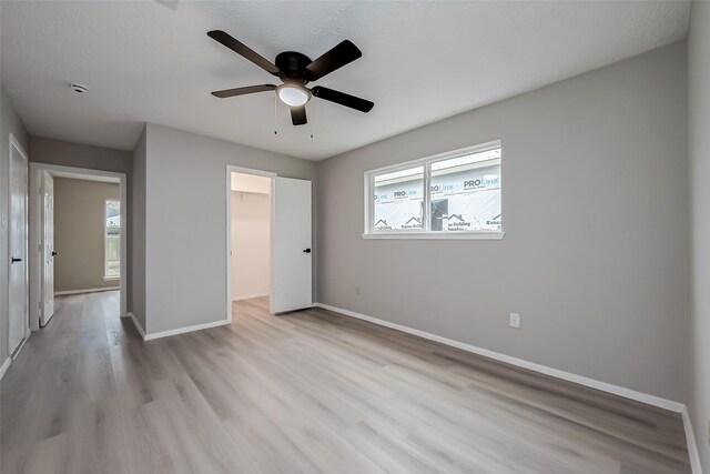 23227 Pine Post Ln, Spring, TX 77373 - unfurnished bedroom with light wood-style flooring, baseboards, a walk in closet, ceiling fan, and a closet