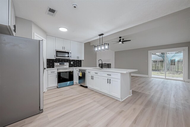23227 Pine Post Ln, Spring, TX 77373 - kitchen with stainless steel appliances, a peninsula, a sink, light wood-type flooring, and a ceiling fan