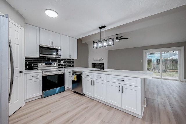 23227 Pine Post Ln, Spring, TX 77373 - kitchen with appliances with stainless steel finishes, a sink, a peninsula, light wood-style floors, and light countertops