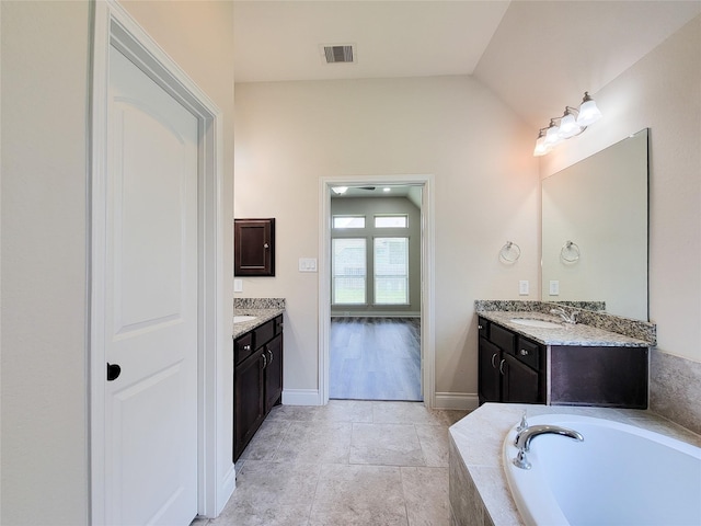 1314 Watercrest Park Ln, Rosenberg, TX 77471 - full bath with two vanities, a garden tub, vaulted ceiling, and baseboards