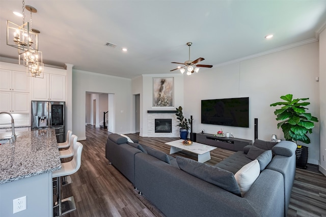 4423 Sterling Heights Ln, Sugar Land, TX 77479 - living area with dark wood finished floors, a stone fireplace, ornamental molding, baseboards, and a ceiling fan