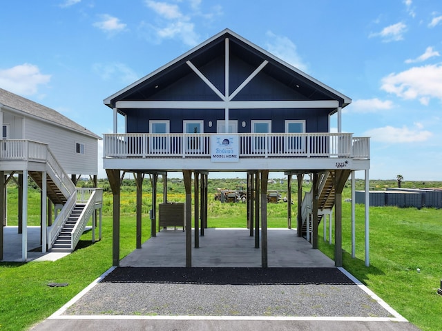 1025 Sunset Cir W, Crystal Beach, TX 77650 - view of front facade with stairway, a carport, board and batten siding, driveway, and a front lawn