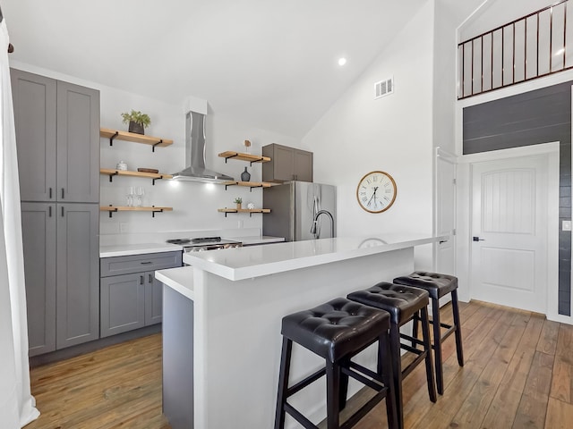 1025 Sunset Cir W, Crystal Beach, TX 77650 - kitchen with island range hood, gray cabinetry, freestanding refrigerator, open shelves, and light wood-style flooring