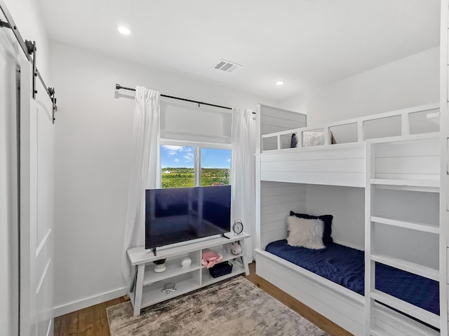 1025 Sunset Cir W, Crystal Beach, TX 77650 - bedroom featuring a barn door, wood finished floors, and recessed lighting