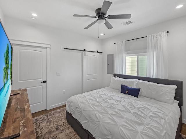 1025 Sunset Cir W, Crystal Beach, TX 77650 - bedroom featuring a barn door, wood finished floors, recessed lighting, and ceiling fan