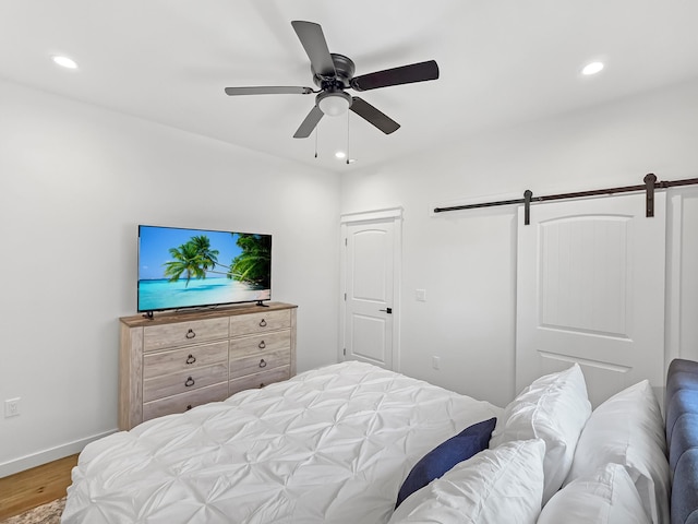 1025 Sunset Cir W, Crystal Beach, TX 77650 - bedroom featuring recessed lighting, wood finished floors, a barn door, and a ceiling fan