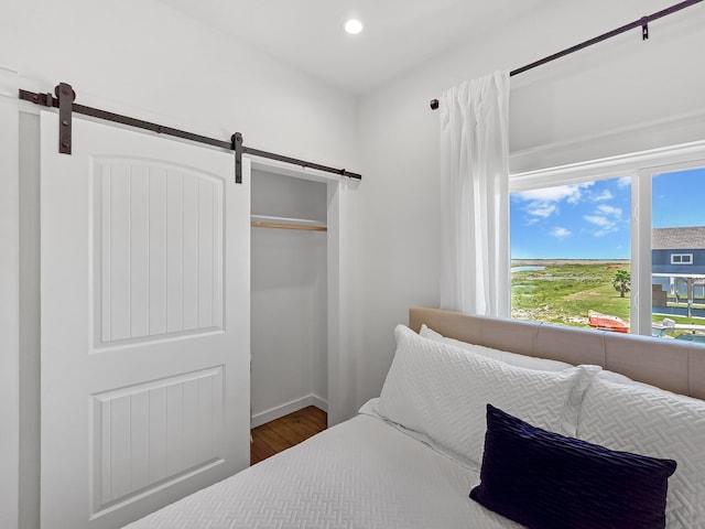 1025 Sunset Cir W, Crystal Beach, TX 77650 - bedroom with a barn door, wood finished floors, recessed lighting, and a closet
