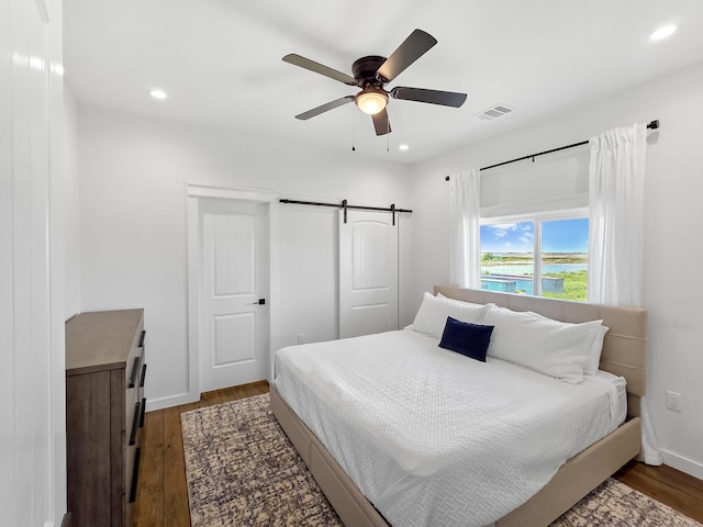 1025 Sunset Cir W, Crystal Beach, TX 77650 - bedroom with wood finished floors, recessed lighting, ceiling fan, and a barn door