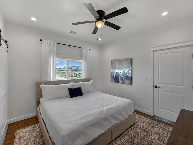 1025 Sunset Cir W, Crystal Beach, TX 77650 - bedroom with a barn door, recessed lighting, wood finished floors, and ceiling fan