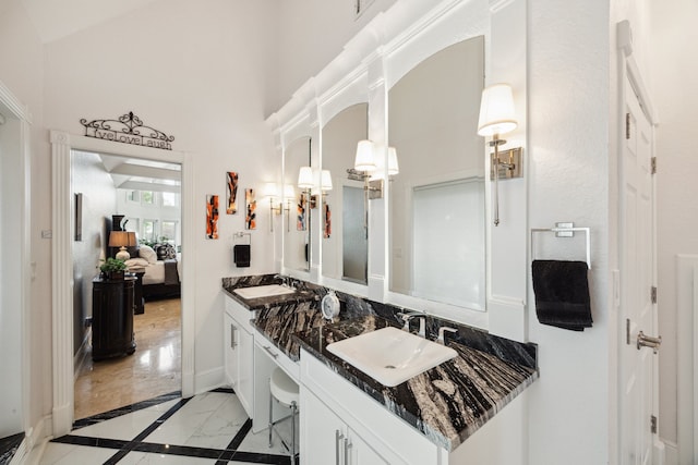 1917 Anchor Way, Dickinson, TX 77539 - ensuite bathroom featuring marble finish flooring, double vanity, inlaid floor details, a towering ceiling, and baseboards