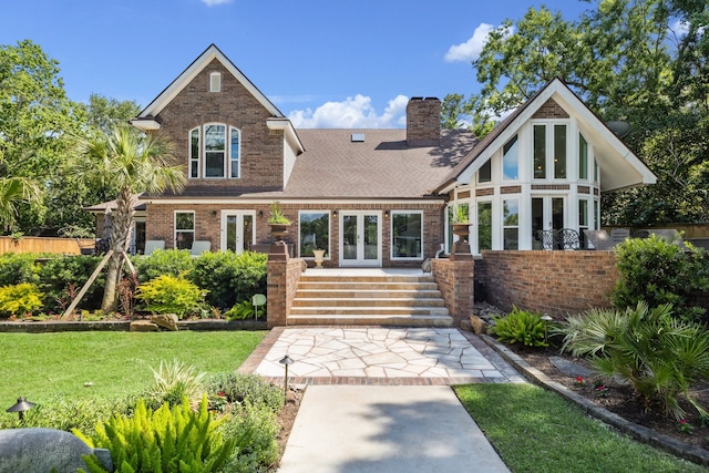 1917 Anchor Way, Dickinson, TX 77539 - rear view of house featuring french doors, brick siding, a chimney, a shingled roof, and a lawn