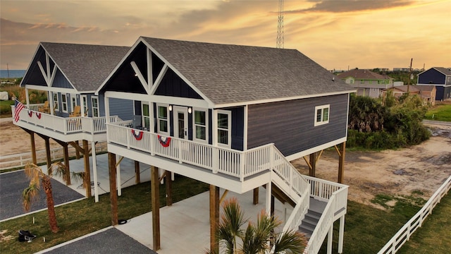 1025 Sunset Cir W, Crystal Beach, TX 77650 - back of property featuring a shingled roof, a carport, a deck, stairs, and board and batten siding
