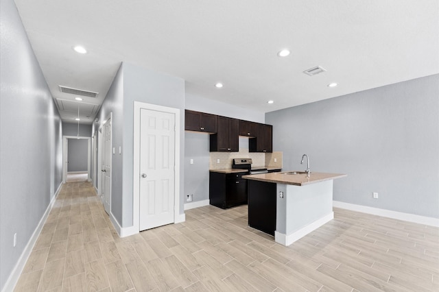 4534 Maggie St, Houston, TX 77051 - kitchen featuring electric range, a sink, light wood-style flooring, decorative backsplash, and an island with sink