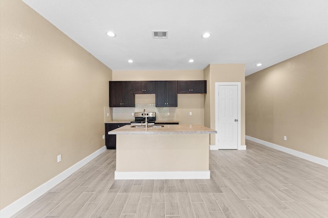 4534 Maggie St, Houston, TX 77051 - kitchen featuring light countertops, a sink, a center island with sink, light wood-style flooring, and recessed lighting