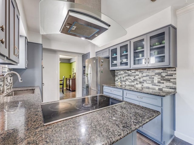 674 Ravensworth Dr, Conroe, TX 77302 - kitchen with freestanding refrigerator, black electric cooktop, a sink, tasteful backsplash, and glass insert cabinets
