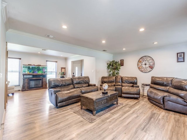 674 Ravensworth Dr, Conroe, TX 77302 - living room featuring crown molding, light wood-style flooring, recessed lighting, and a glass covered fireplace