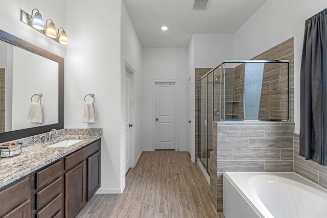 15010 Lake Shore Ave, Mont Belvieu, TX 77523 - bathroom featuring a bath, vanity, a stall shower, wood finish floors, and baseboards