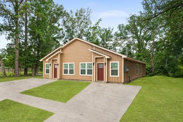 9303 Firnat St, Houston, TX 77016 - view of front of property with driveway, board and batten siding, and a front lawn