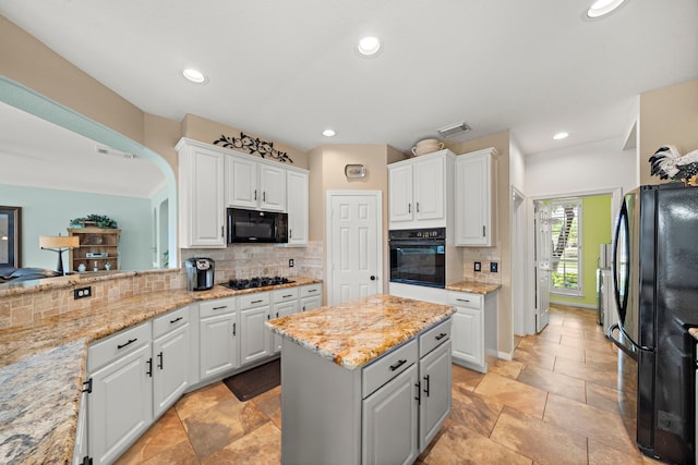 20306 Silverwood Trl, Cypress, TX 77433 - kitchen with black appliances, white cabinets, tasteful backsplash, a kitchen island, and light stone counters