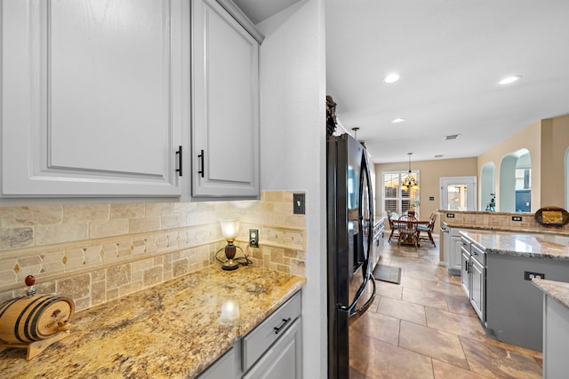 20306 Silverwood Trl, Cypress, TX 77433 - kitchen with black fridge with ice dispenser, tasteful backsplash, recessed lighting, light stone counters, and pendant lighting
