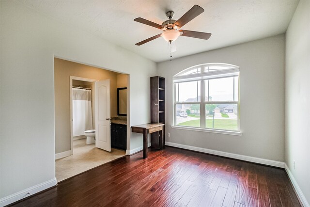 13918 Twisting Ivy Ln, Cypress, TX 77429 - unfurnished bedroom with hardwood / wood-style flooring, baseboards, ensuite bath, and a ceiling fan