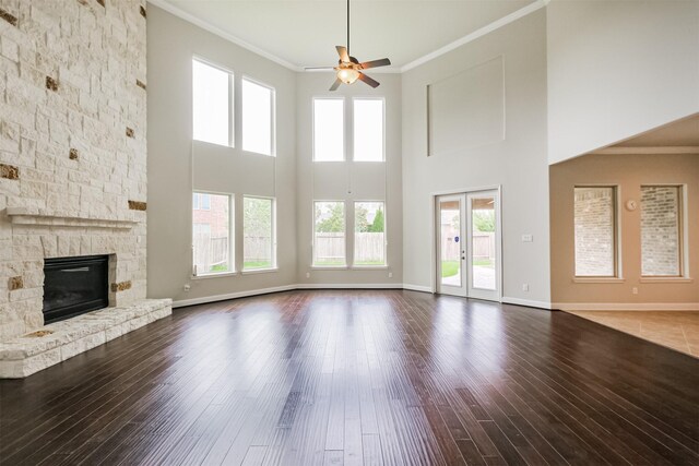 13918 Twisting Ivy Ln, Cypress, TX 77429 - unfurnished living room with a ceiling fan, ornamental molding, a stone fireplace, wood finished floors, and baseboards