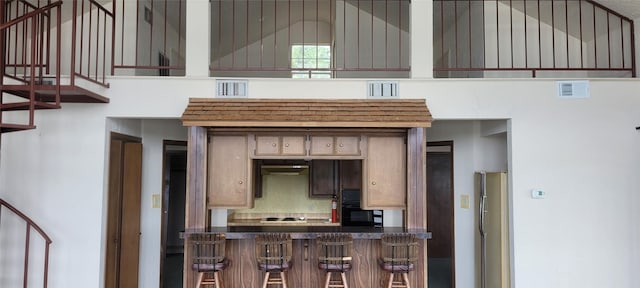 15088 Cozy Cove Ln, Willis, TX 77318 - kitchen with cooktop, a kitchen breakfast bar, freestanding refrigerator, dark countertops, and high vaulted ceiling